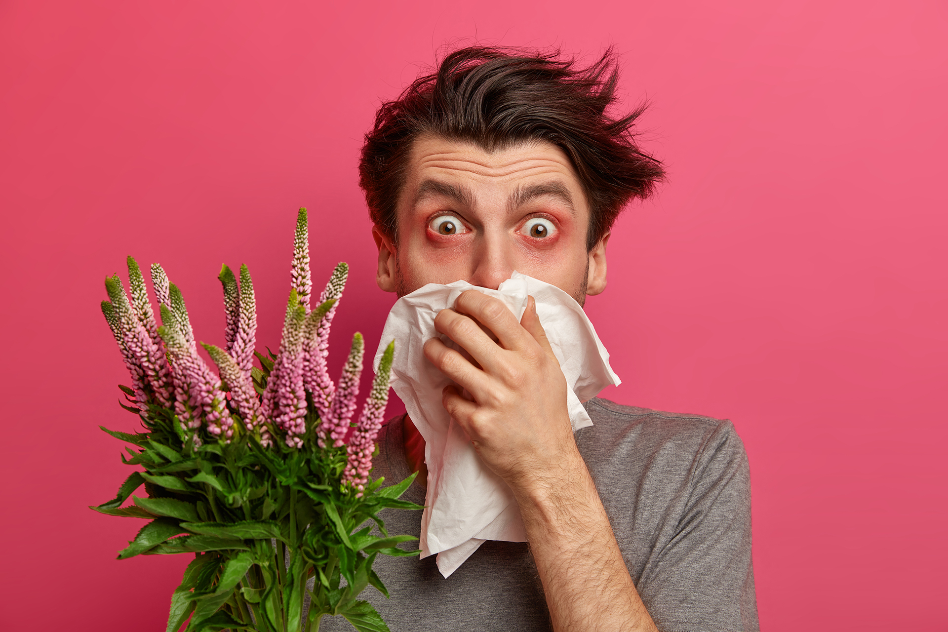 Человек с букетом чихает аллергия.